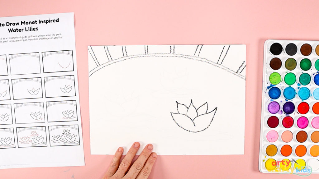 Features a hand using a printed how-to-draw guide to draw the water lily.