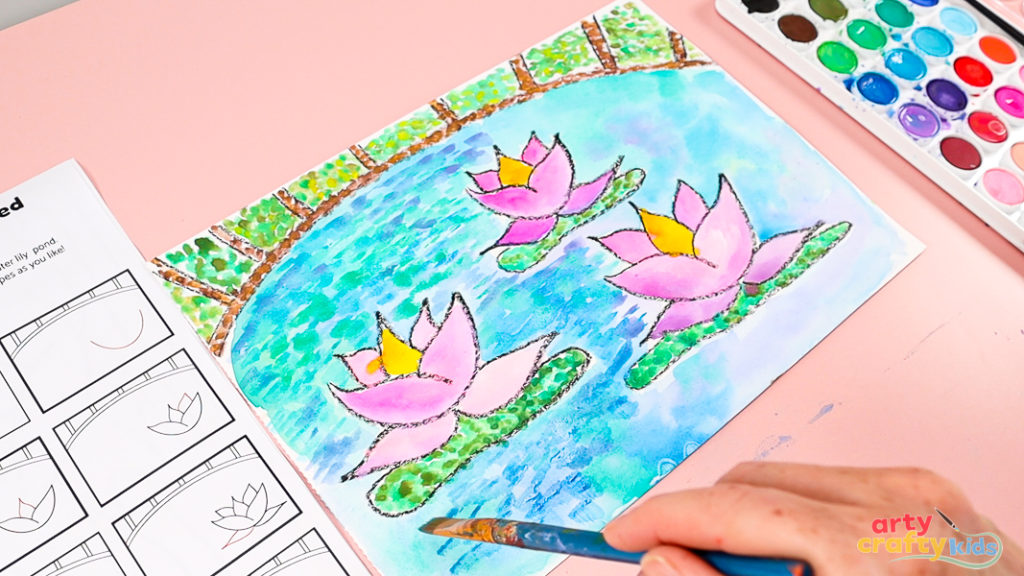 Image of a hand layering blue paint with a flat-tipped brush over the watercolor pond.
