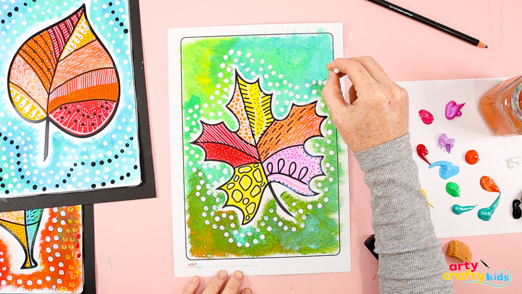 Hand using a q-tip to add a collection of white dots around the pattern leaf design. 