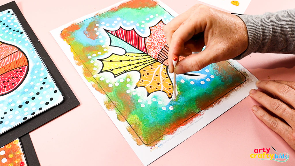 Hand using a q-tip to add a collection of white dots around the pattern leaf design. 
