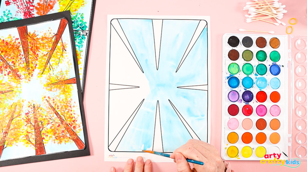 Painting the background sky area blue with watercolors.