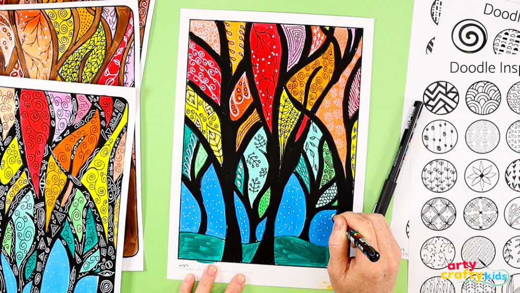 Hand using a marker to add doodle patterns onto colorful fall tree painting with black trunks