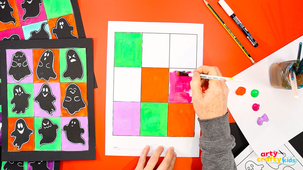 Painting a Pop Art-style grid in Halloween colors of orange, green, purple, and black for a ghost art project inspired by Andy Warhol.